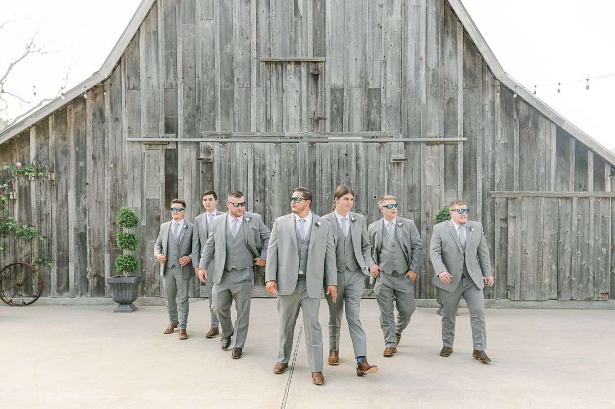 groomsmen in grey in front of old barn in Pattison, Tx