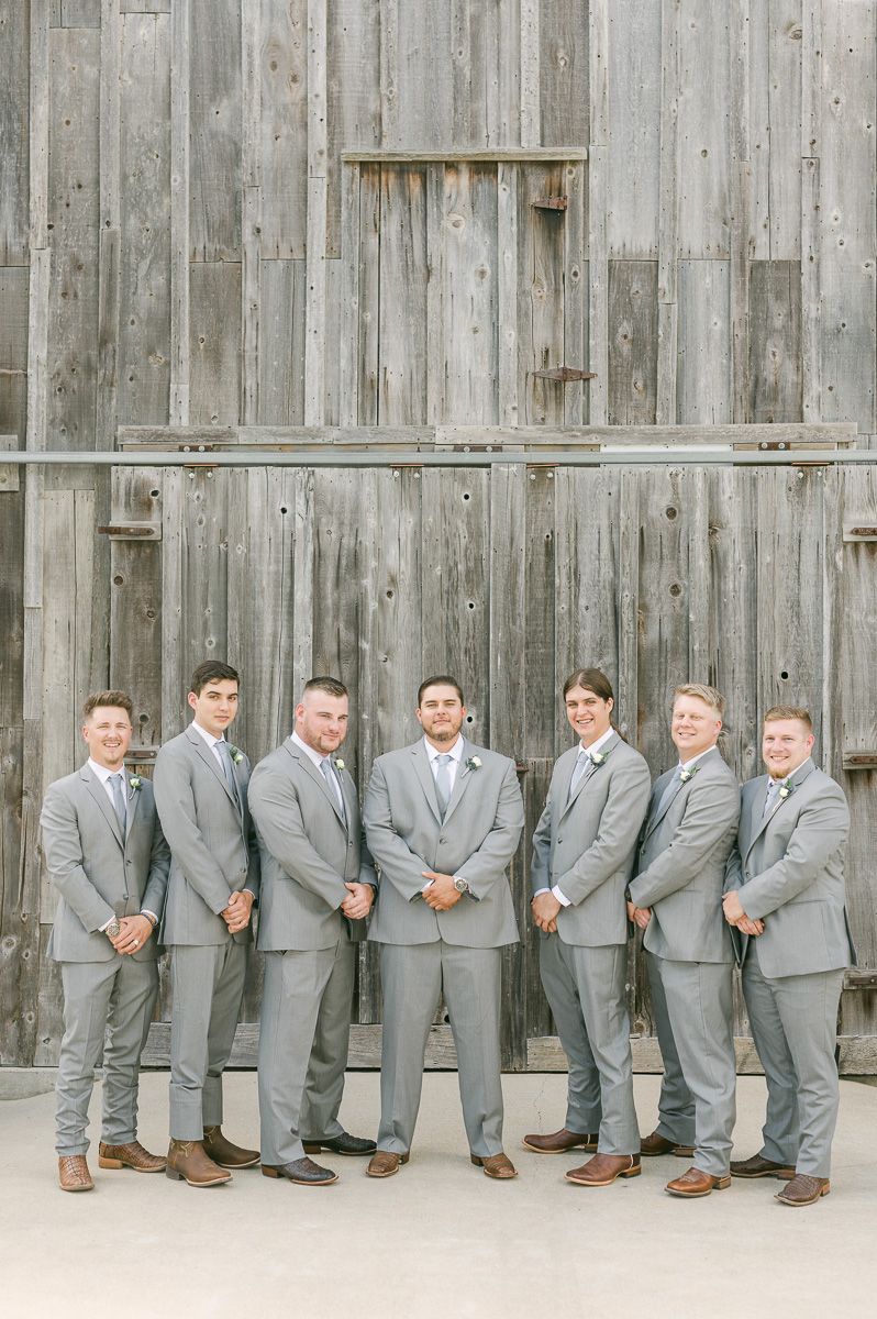 groomsmen in grey in front of old barn in Pattison, Tx