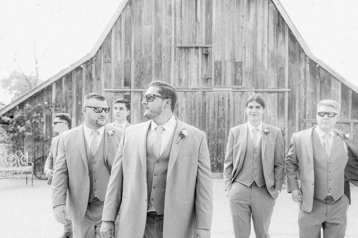 groomsmen in grey in front of old barn in Pattison, Tx