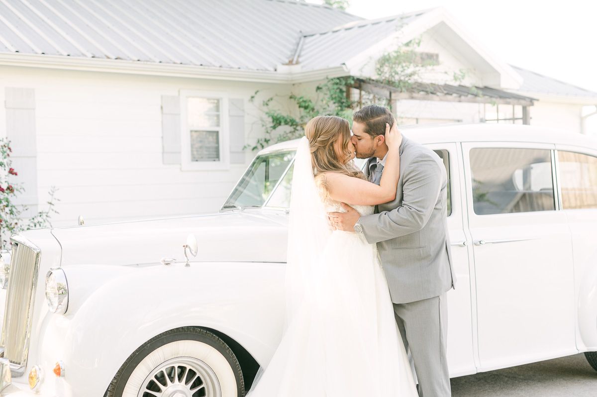 bride and groom with white classic car
