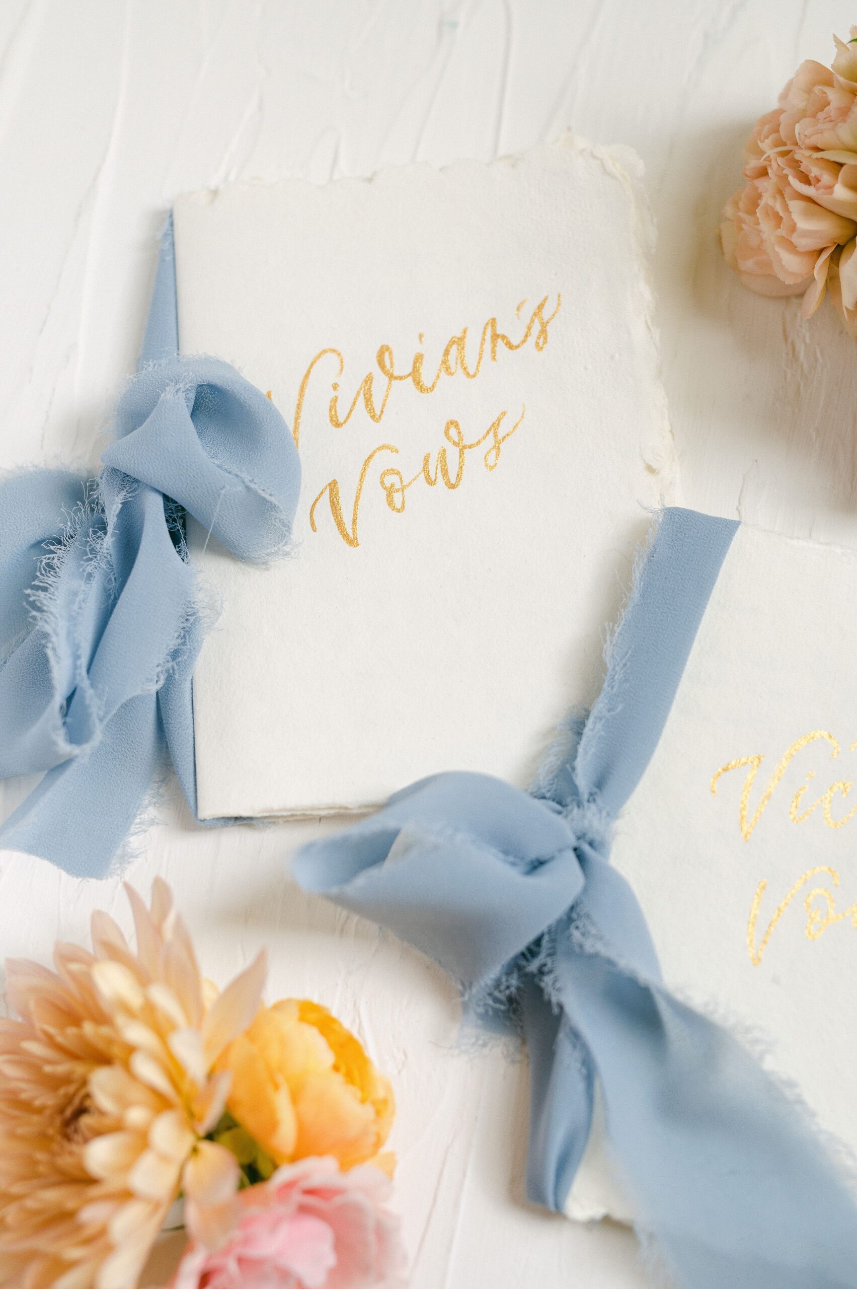 vow books with blue ribbon and colorful flowers
