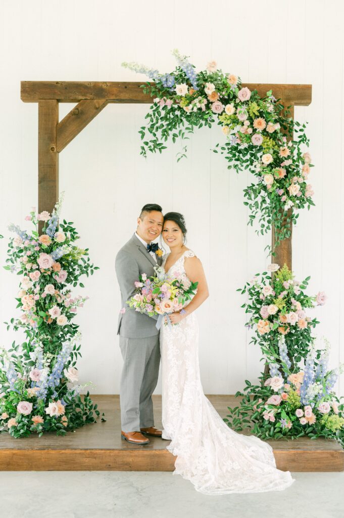 bride and groom in front of colorful wedding flowers