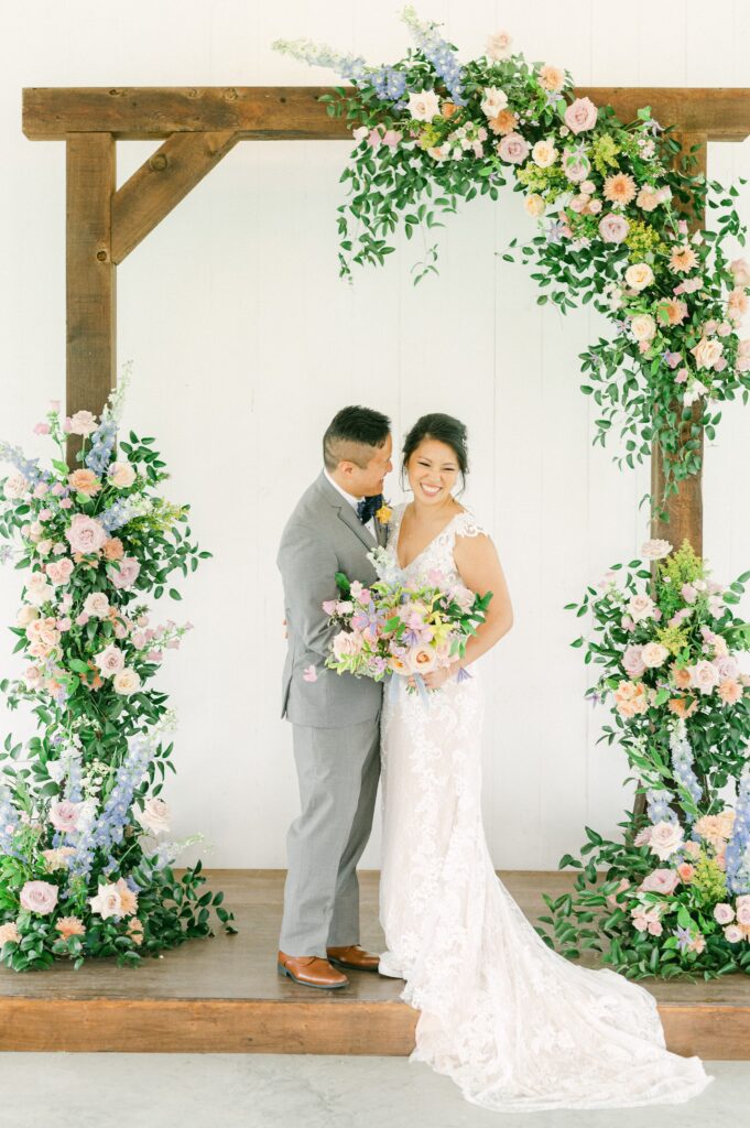 bride and groom in front of colorful wedding flowers