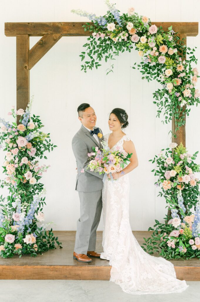 bride and groom in front of colorful wedding flowers
