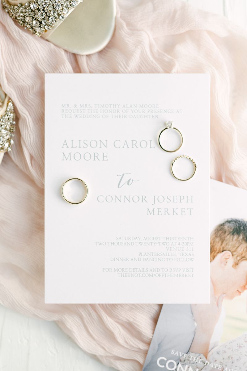 wedding invitation and rings on pink fabric