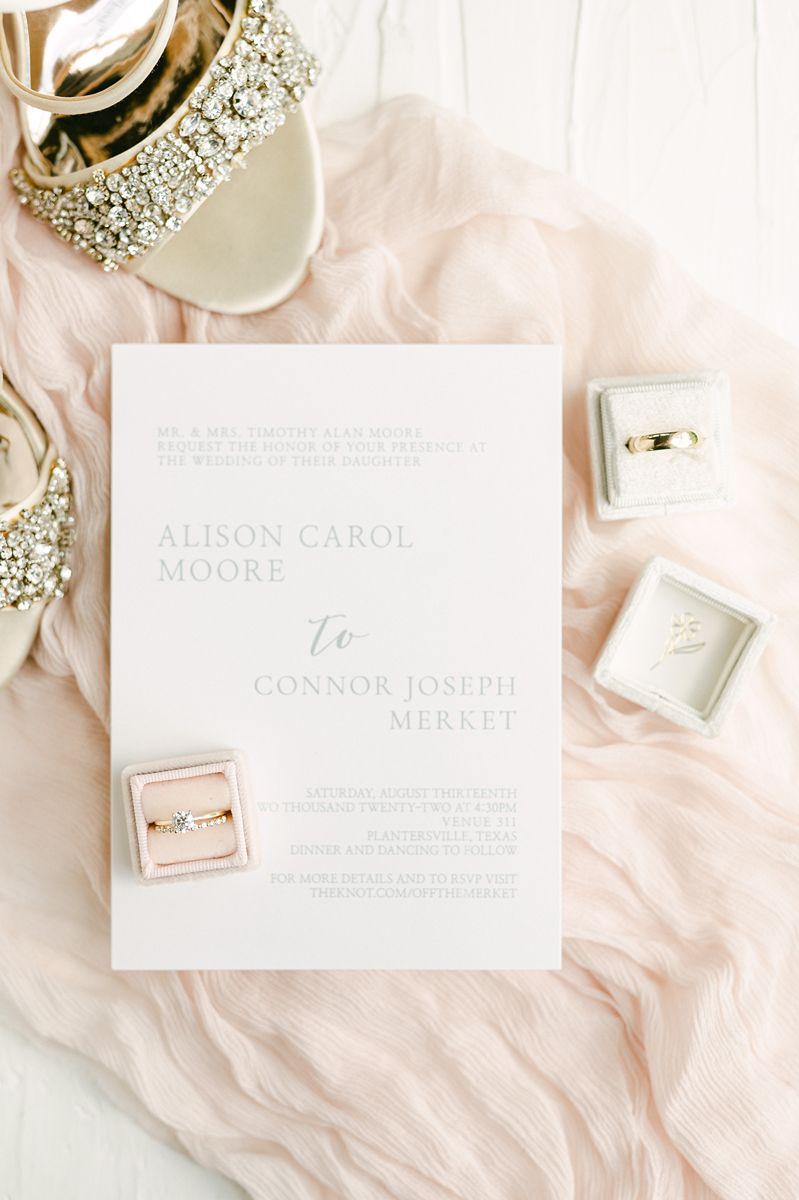 wedding invitation and rings on pink fabric