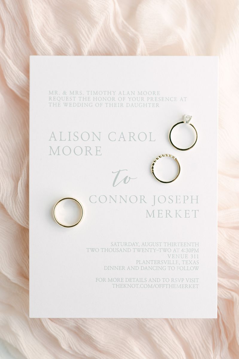 wedding invitation and rings on pink fabric
