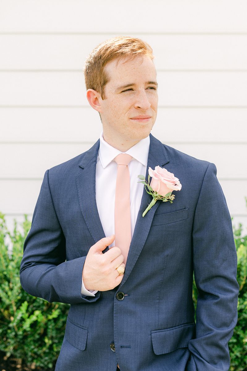 groom in navy blue with pink tie