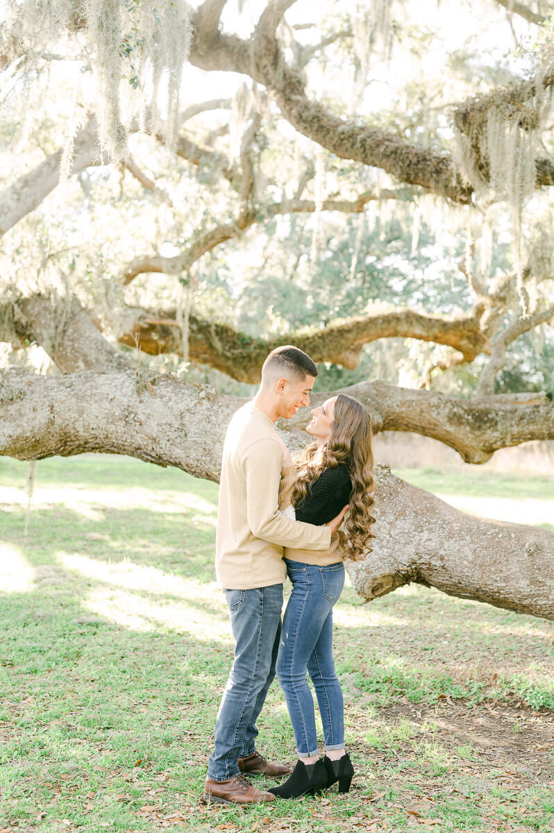 a couple standing in front of a Spanish moss tree