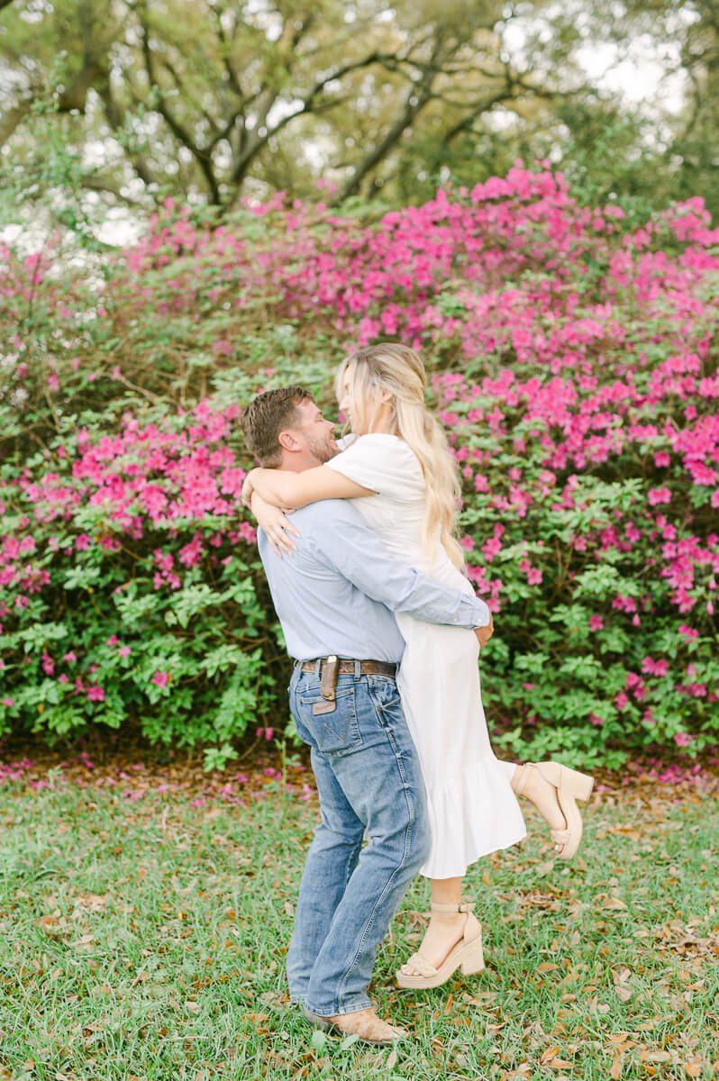 a couple spinning in front of pink flowers at their engagement session