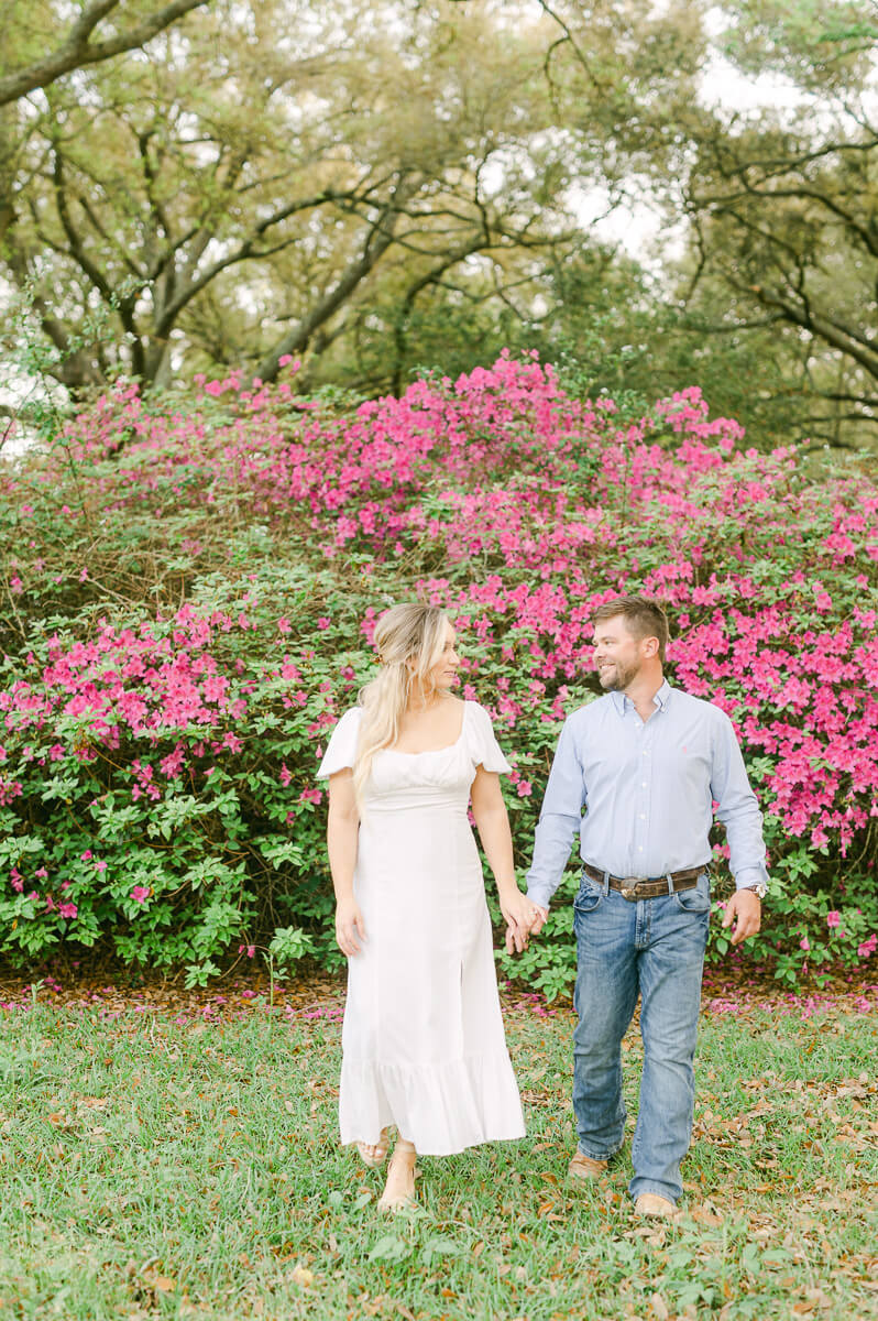 a couple walking in front of pink flowers at their engagement session