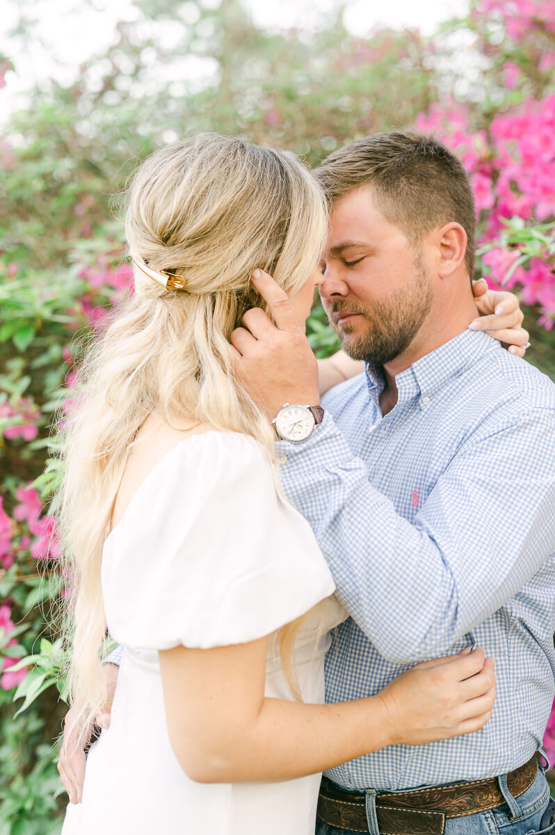 a couple in front of pink flowers at their engagement session