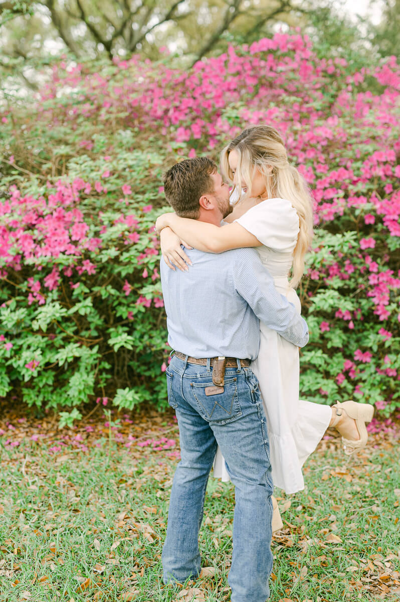 a couple in front of pink flowers at their engagement session