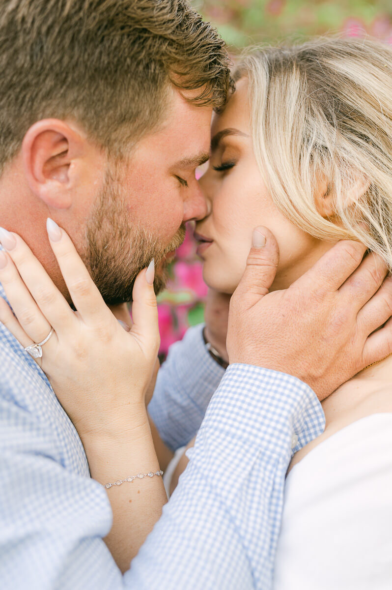 a couple in front of pink flowers at their engagement session