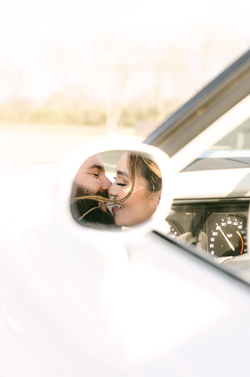 couple at the farmhouse wedding venue with vintage car