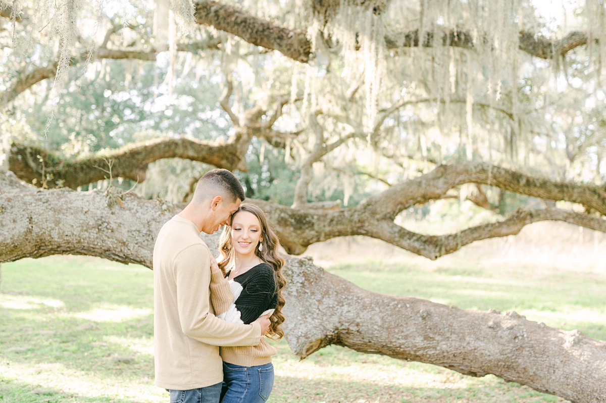 a couple in front of tree covered in Spanish moss 