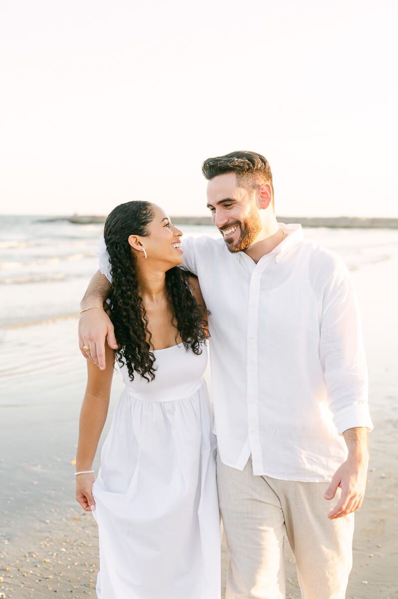 couple walking on Galveston beach at their engagement photography session