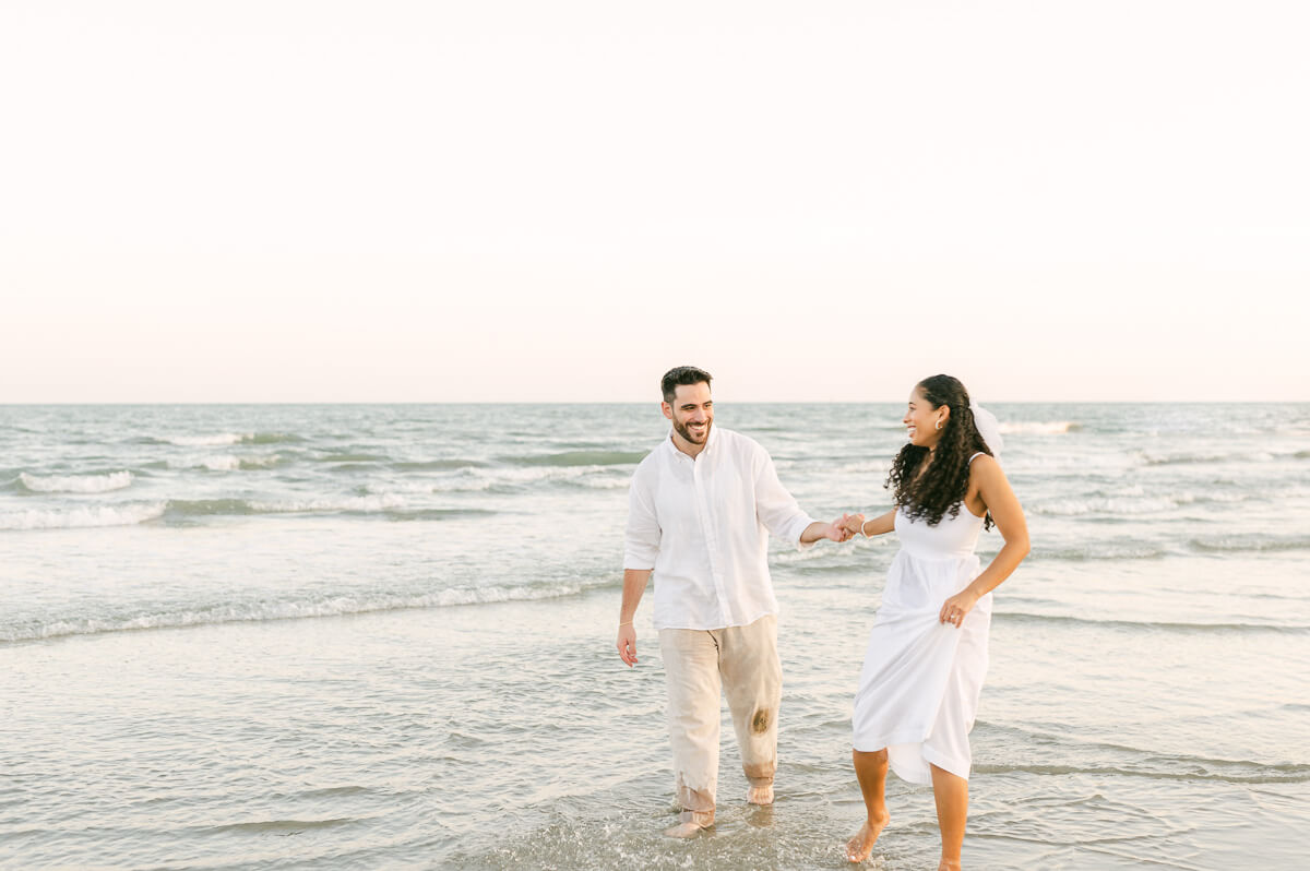 couple running through the water on Galveston beach