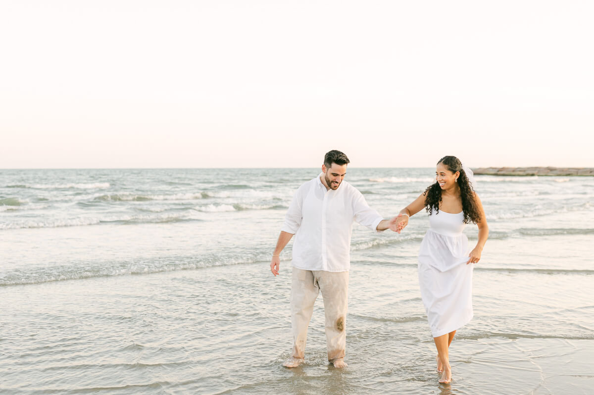 couple running through the water on Galveston beach