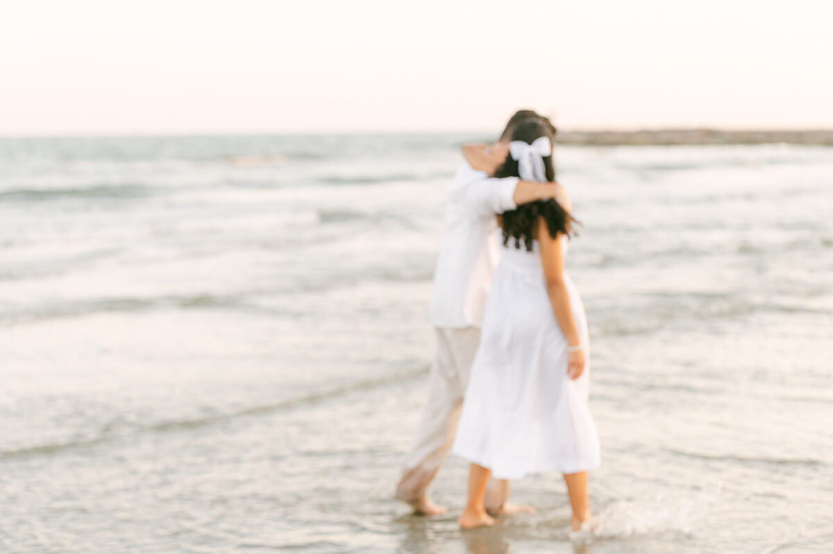 couple walking through the water on Galveston beach