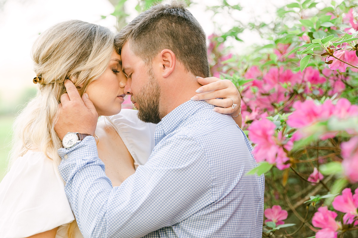 a couple in front of pink flowers at their engagement session