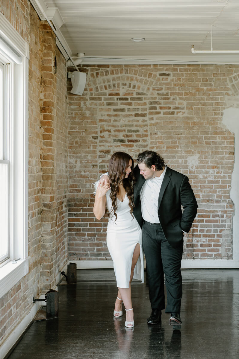 a couple walking in front of a brick wall 