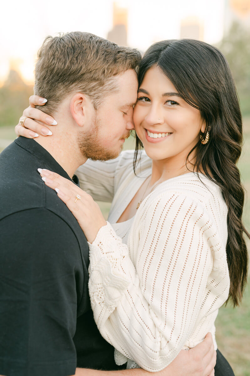 an engaged couple with the houston skyline behind them