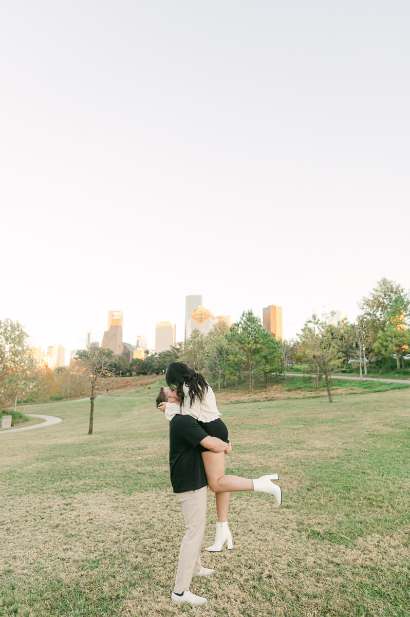 an engaged couple with the houston skyline behind them