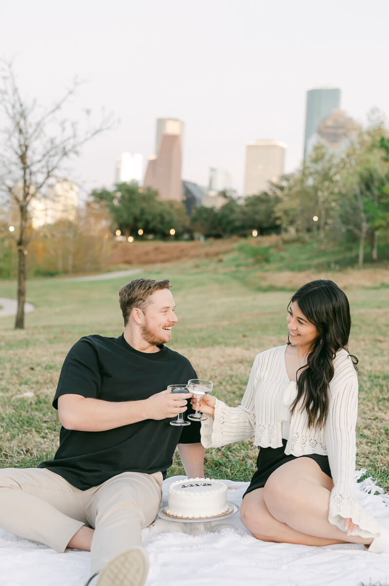 a couple with cake and champagne in front of the houston city skyline