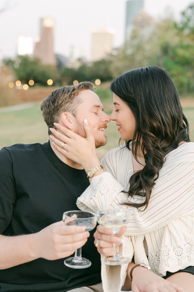 a couple with cake and champagne in front of the houston city skyline