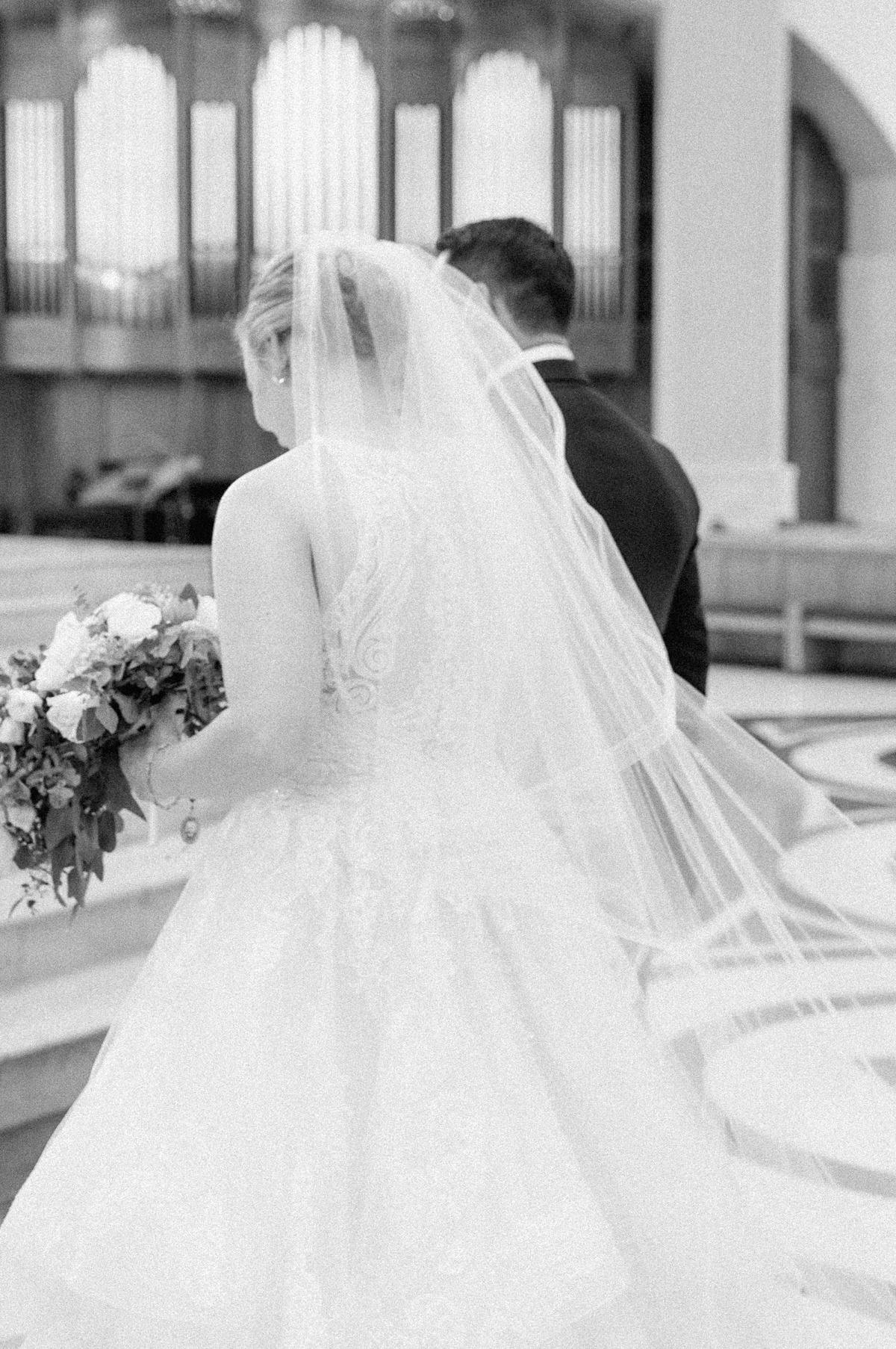 black and white photo of a groom helping his bride up the alter steps