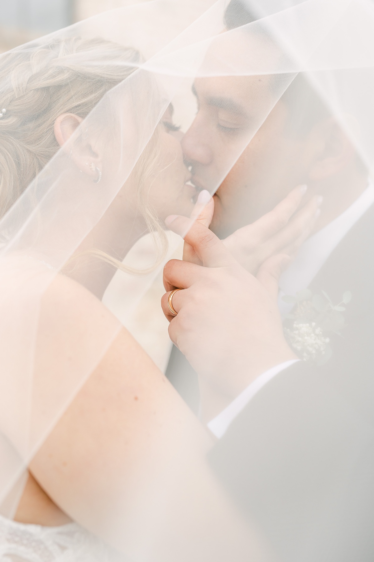 romantic couple under the veil as they kiss at their wedding