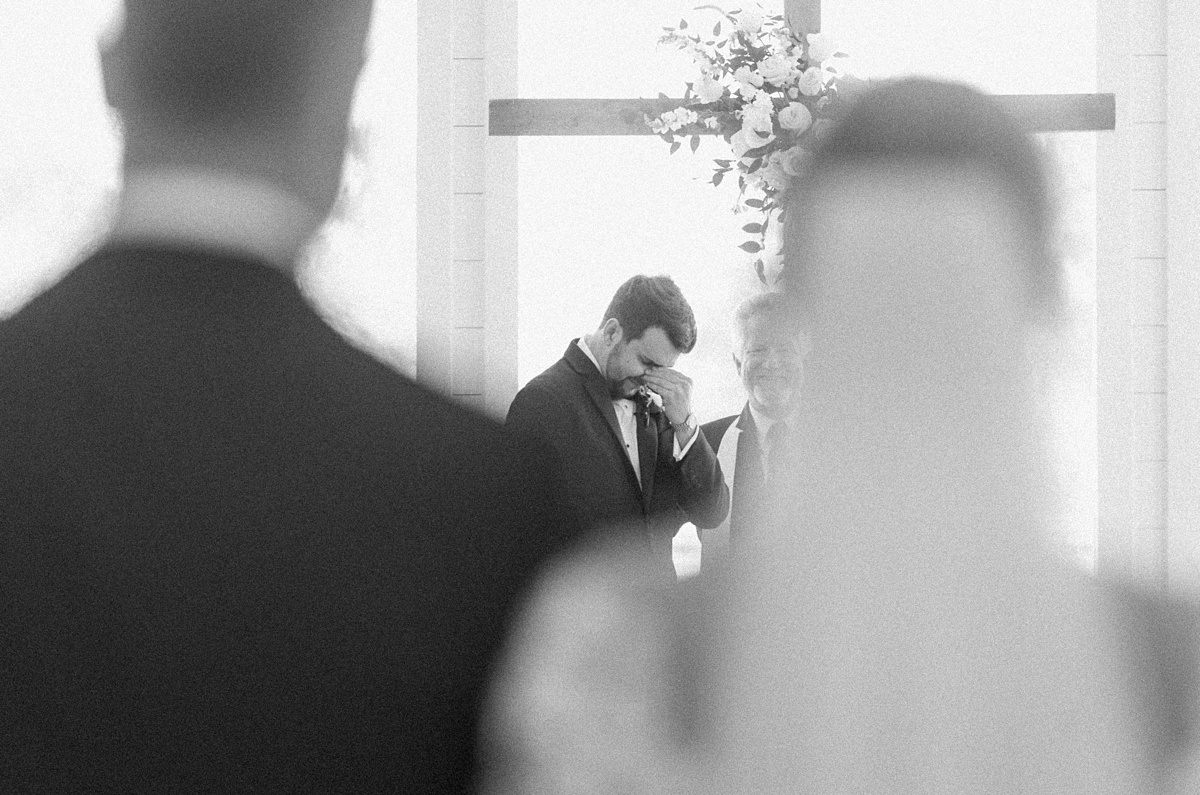 a groom crying as he sees his bride