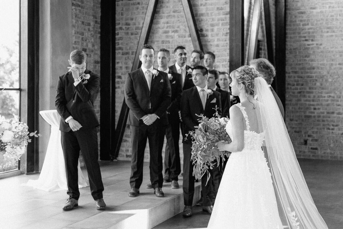 groom crying seeing his bride walk down the aisle