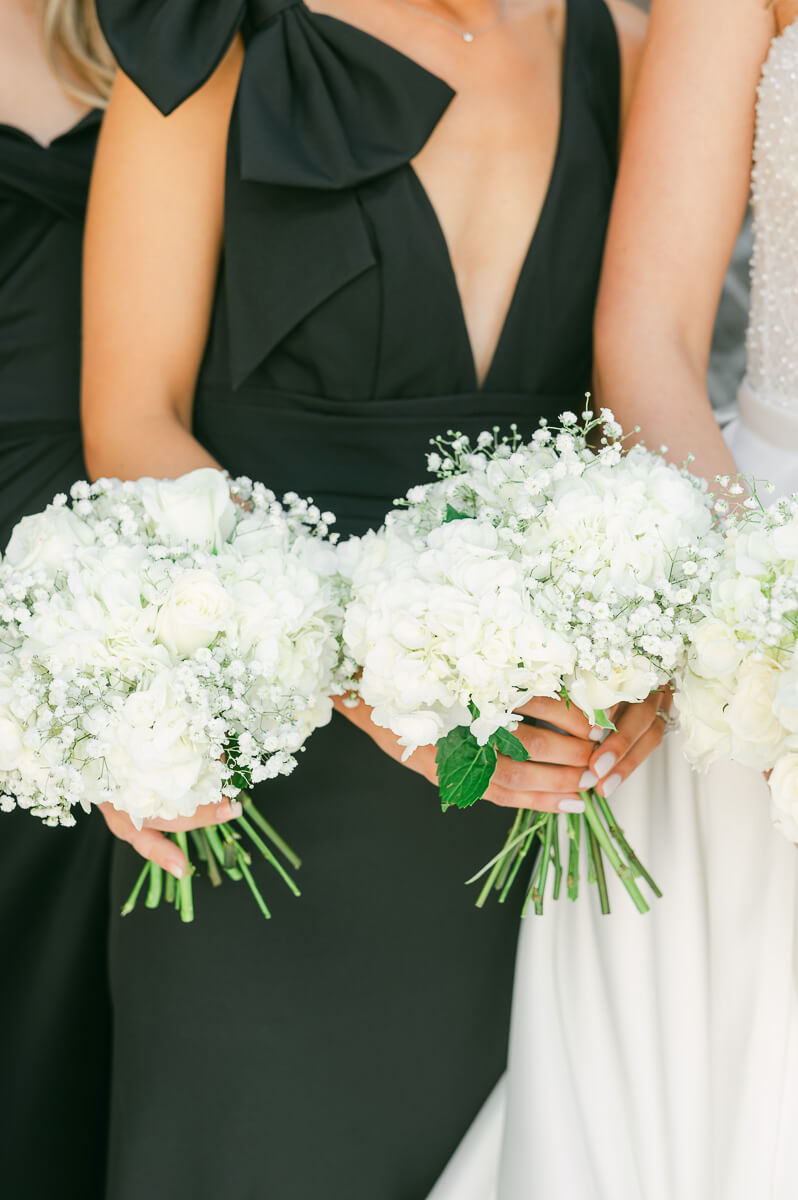 bridesmaids wearing black holding flowers