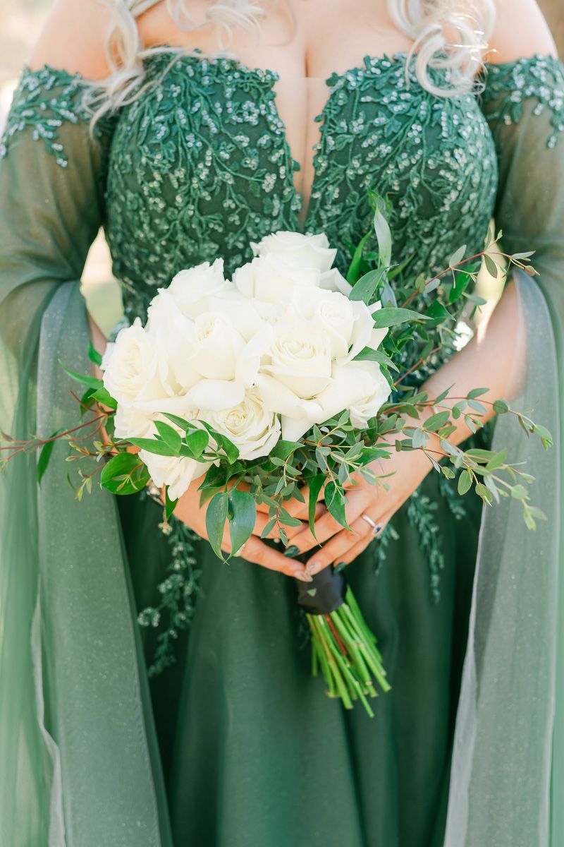 bride wearing emerald green wedding dress holding white flowers