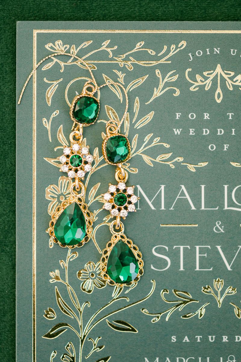 emerald earrings on green gold foiled wedding invitation