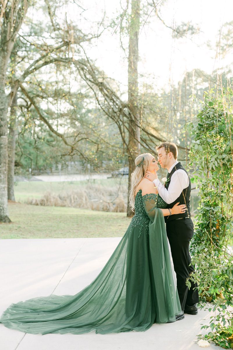 bride wearing emerald green dress and hugging groom