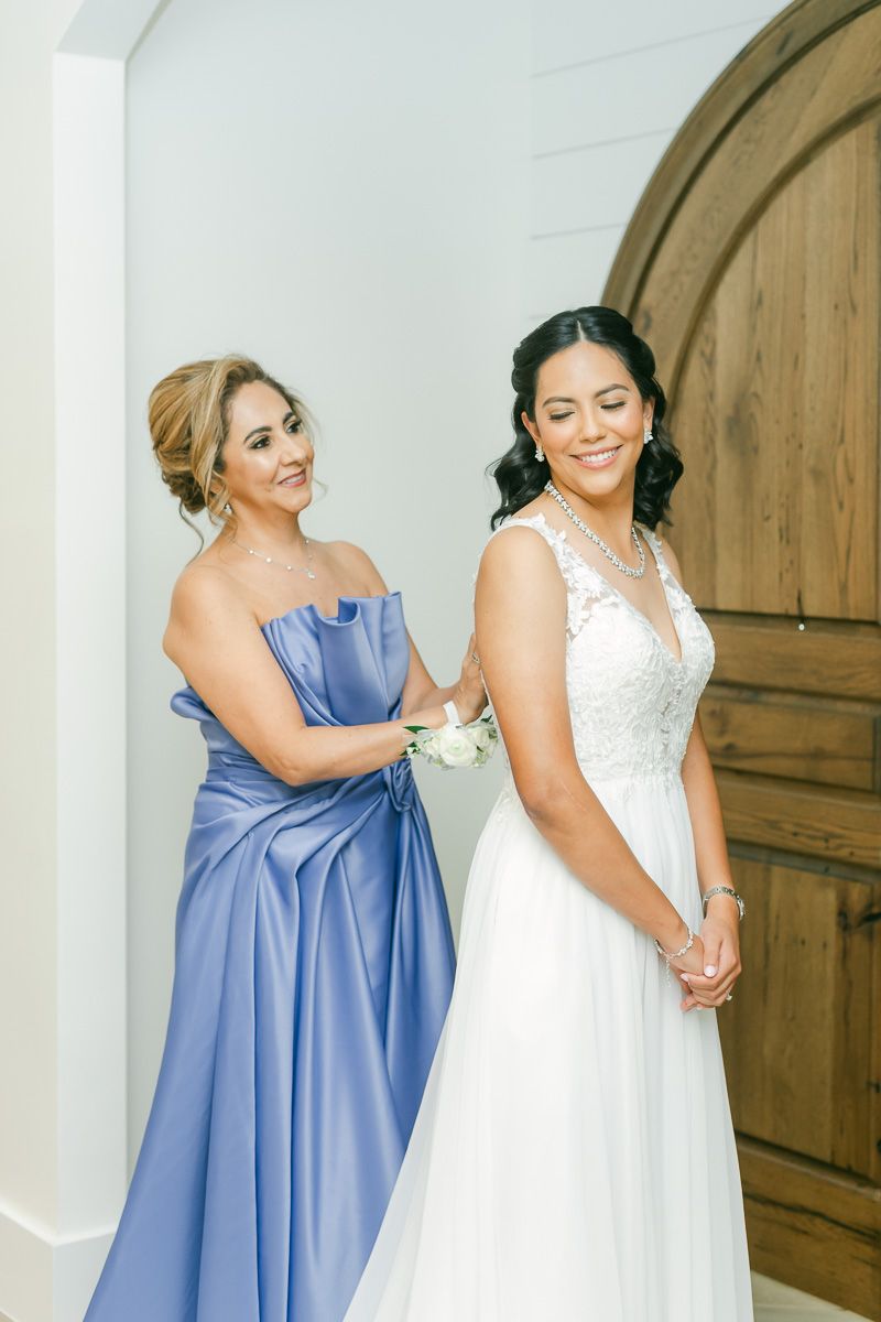 bride getting into dress at The Blue Magnolia wedding venue