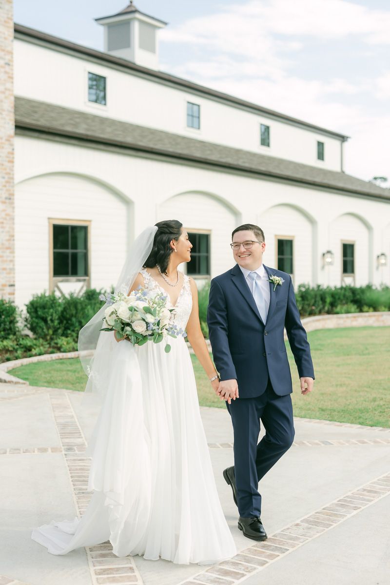 bride and groom walking in front of The Blue Magnolia wedding venue