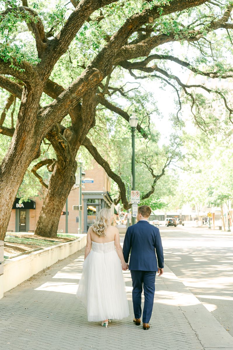 bride and groom walking outside the 1910 Harris County Courthouse 