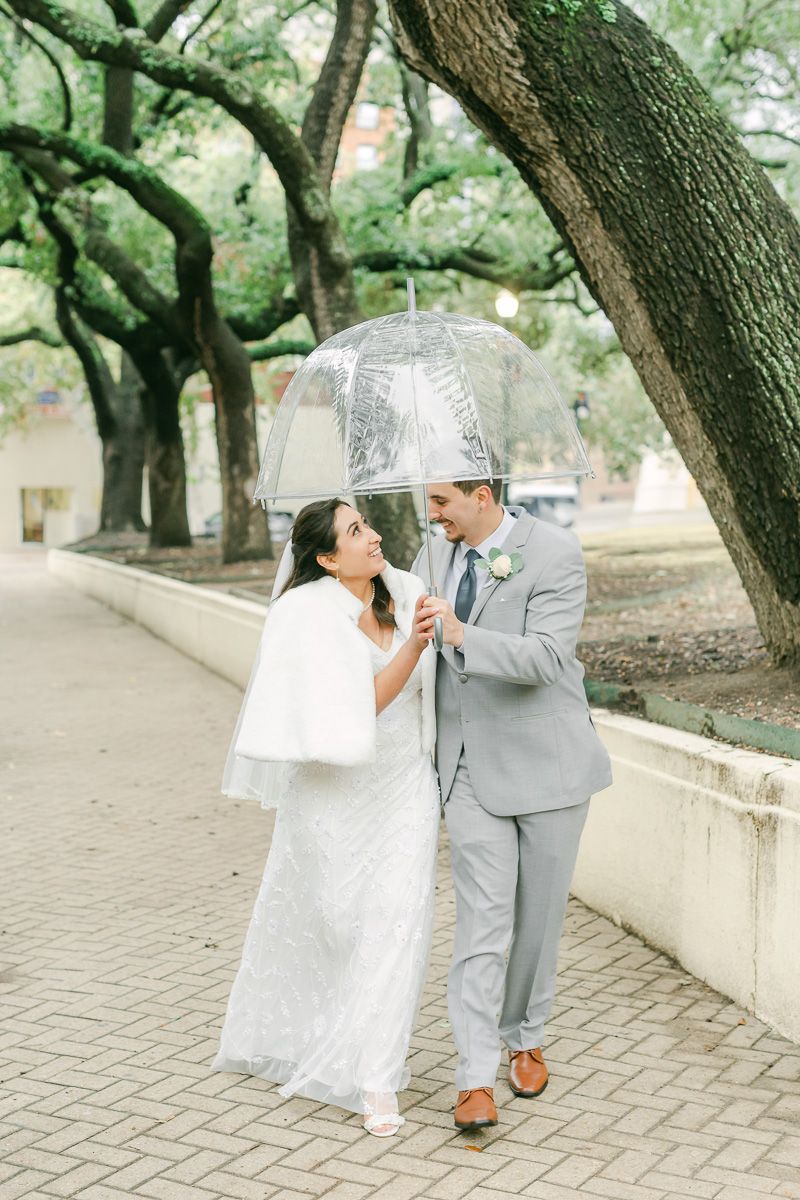 bride and groom walking outside the Houston courthouse with umbrella